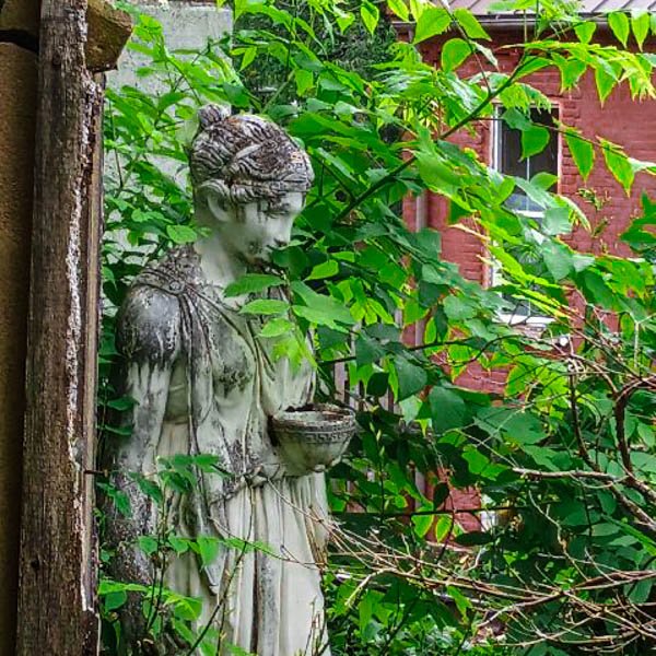 a statue of a woman hidden behind plants